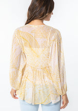 [Color: Natural/Mustard] A model wearing a yellow leaf print sheer chiffon bohemian blouse with gold metallic clip dot details throughout. With long voluminous sleeves and a ruffle trimmed waist. 