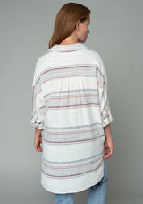 [Color: Ivory/Red] A woman wearing an off white oversized tunic shirt with red striped detail.