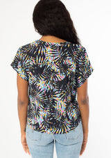 [Color: Black/Blue] A back facing image of a black model wearing a multicolor black and blue palm print short sleeve top with a button front and a tie front waist detail. 