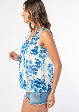 [Color: Cream/Blue] A model wearing a sheer chiffon sleeveless bohemian blouse in a white and blue watercolor floral print. 