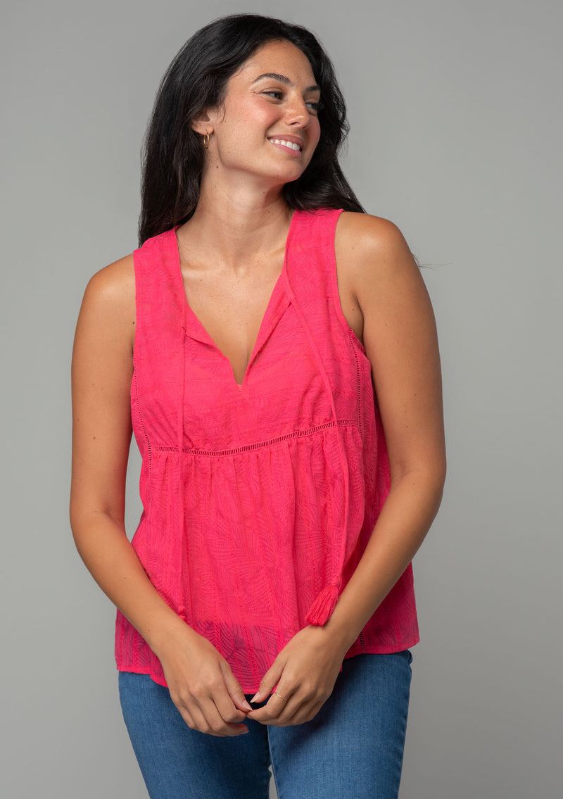 [Color: Watermelon] A front facing image of a brunette model with long wavy dark hair wearing a bright pink bohemian sleeveless tank top with a split v neckline and tassel ties.