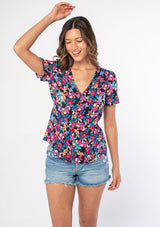 [Color: Black/Fuchsia] A woman wearing a black and pink floral print peplum top with short sleeves and a button front. 