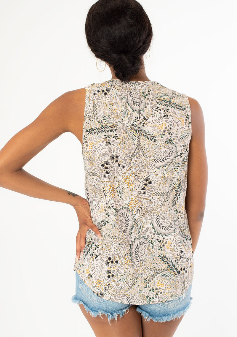 [Color: Natural/Olive] A back facing image of a black model wearing a natural and olive green floral print sleeveless tank top with a relaxed fit and a split v neckline. 