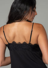 [Color: Black] A close up back facing image of a brunette model wearing a black lace trim camisole with a v neckline, adjustable spaghetti straps, and a flowy relaxed fit. 