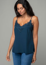 [Color: Midnight] A front facing image of a brunette model wearing a navy blue lace trim camisole with a v neckline, adjustable spaghetti straps, and a flowy relaxed fit. 