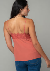 [Color: Rosewood] A back facing image of a brunette model wearing a dusty rose pink lace trim camisole with a v neckline, adjustable spaghetti straps, and a flowy relaxed fit. 
