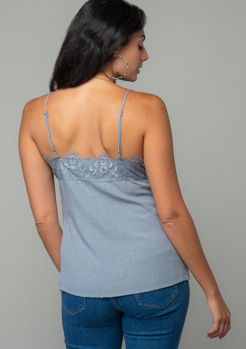 [Color: Grey] A back facing image of a brunette model wearing a light grey clip dot camisole with a lace trim v neckline and adjustable spaghetti straps. 