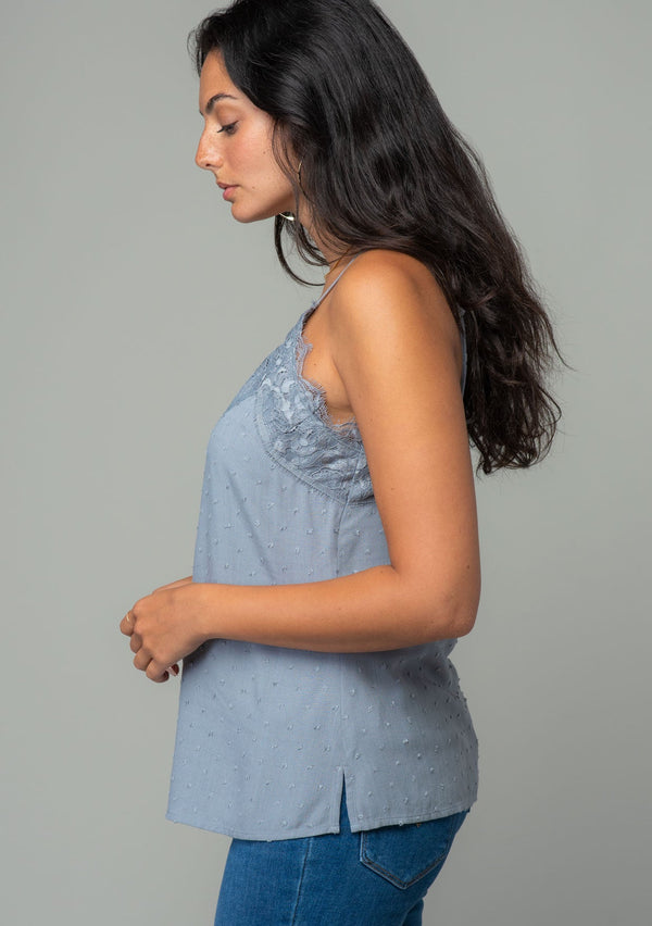 [Color: Grey] A side facing image of a brunette model wearing a light grey clip dot camisole with a lace trim v neckline and adjustable spaghetti straps. 