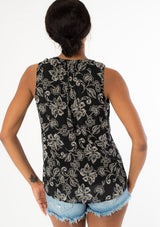 [Color: Black/Natural] A back facing image of a black model wearing a classic sleeveless bohemian tank top in a black and natural, off white floral print. A flowy chiffon top with a button front and loop button trimmed v neckline. 