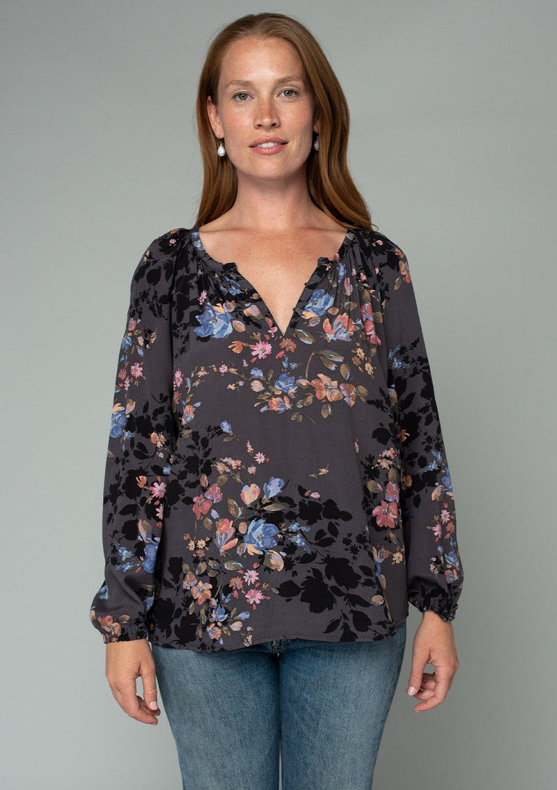 [Color: Grey/Dusty Blue] A half body front facing image of a red headed model wearing a classic bohemian peasant blouse in a grey and blue floral print. With long voluminous raglan sleeves and a front placket with a hook and eye closure. 