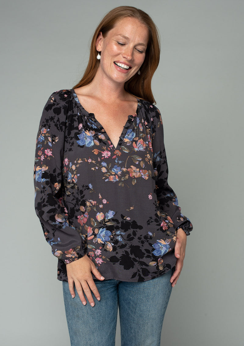 [Color: Grey/Dusty Blue] A front facing image of a red headed model wearing a classic bohemian peasant blouse in a grey and blue floral print. With long voluminous raglan sleeves and a front placket with a hook and eye closure. 