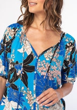 [Color: Turquoise/Black] A woman wearing a flowy bohemian top in a blue and black large floral print. With half length puff sleeves and a button front. 