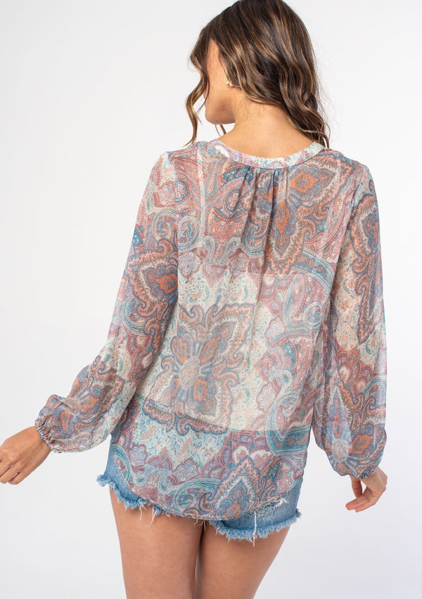 [Color: Blush/Aqua] A woman wearing a bohemian sheer pink paisley peasant top with long sleeves and a v neckline. 