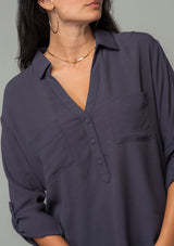 [Color: Charcoal] A close up front facing image of a brunette model wearing a relaxed fit charcoal grey button front shirt in a lightweight crepe. With long rolled sleeves, a button tab sleeve closure, a front placket, and a collared neckline. 