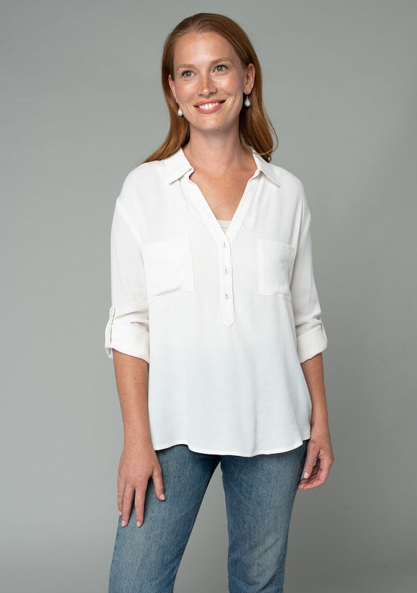 [Color: Gardenia] A half body image of a red headed model wearing a relaxed fit ivory white button front shirt in a lightweight crepe. With long rolled sleeves, a button tab sleeve closure, a front placket, and a collared neckline.