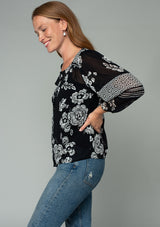 [Color: Black/Cream] A side facing image of a red headed model wearing a bohemian chiffon blouse in a black and cream mixed floral print. With a button front and three quarter length sleeves. 
