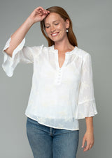 [Color: Ivory] A half body front facing image of a red headed model wearing an ivory off white holiday blouse in embroidered chiffon. With three quarter length sleeves, a flutter wrist cuff, self covered button front, and a flowy fit. 