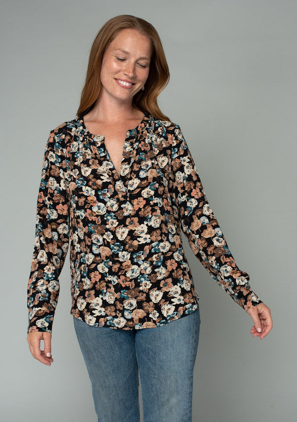 [Color: Black/Natural] A half body front facing image of a red headed model wearing a lightweight long sleeve top in a black and natural floral print. With a split v neckline and a relaxed flowy fit. 
