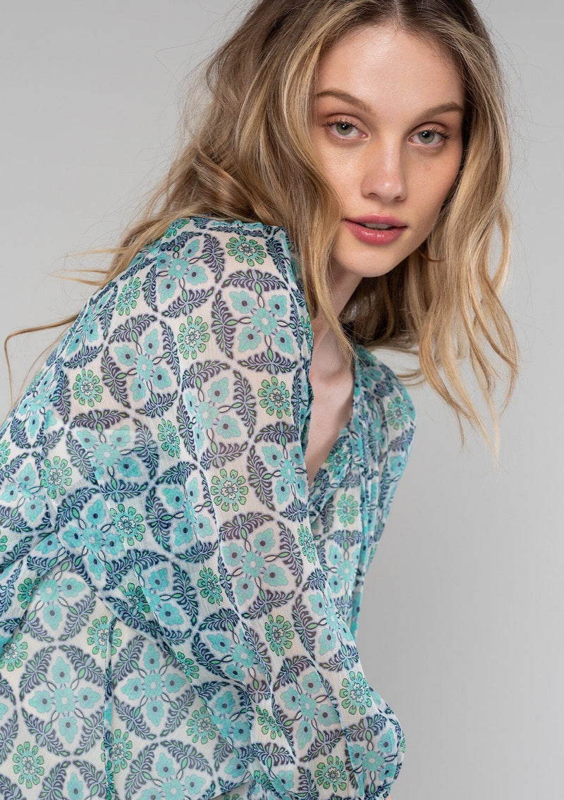 [Color: Cream/Navy] A close up side facing image of a blonde model wearing a sheer chiffon bohemian blouse in a blue floral geometric print. With three quarter length sleeves and a split neckline with ties. 