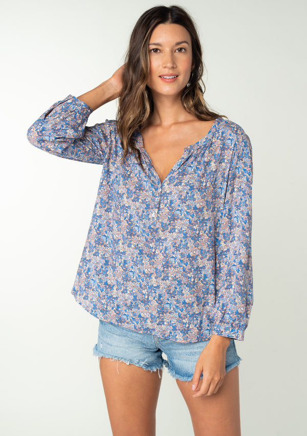 [Color: Blue/Coral] A front facing image of a brunette model wearing a blue and coral floral print bohemian blouse. With long sleeves and a button front. 