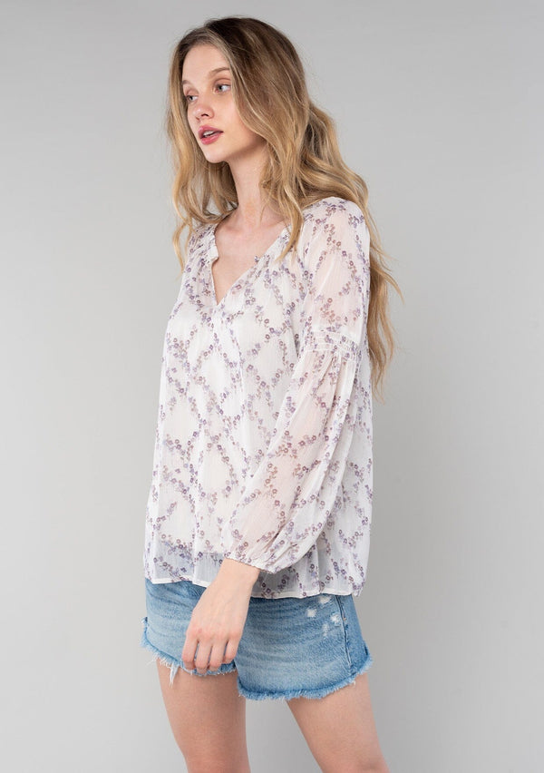 [Color: Ivory/Plum] A half body front facing image of a blonde model wearing a sheer chiffon spring bohemian blouse in an ivory and plum purple floral print. With long bishop sleeves, a wide smocked elastic neckline, a front keyhole detail with button closure, and a flowy relaxed fit. 