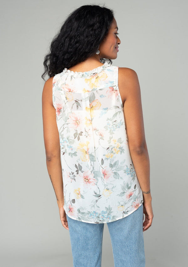 [Color: Natural/Dusty Sage] A back facing image of a brunette model wearing a sleeveless chiffon tank top in a natural and sage green floral print. With a ruffle trimmed neckline, a button front, and a split neckline. 