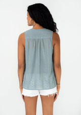 [Color: Dusty Teal] A back facing image of a brunette model wearing a spring sleeveless blouse in a dusty teal eyelet lace chiffon. With a button front, a split v neckline, and a relaxed fit. 