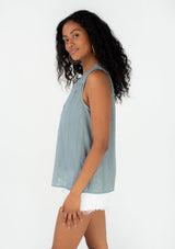 [Color: Dusty Teal] A side facing image of a brunette model wearing a spring sleeveless blouse in a dusty teal eyelet lace chiffon. With a button front, a split v neckline, and a relaxed fit. 