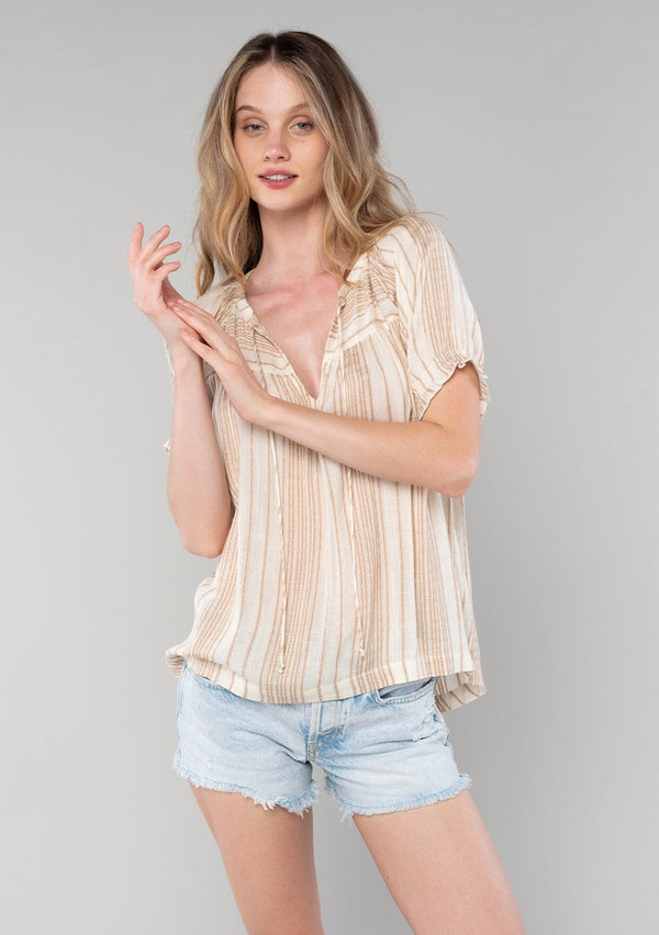 [Color: Natural/Tan] A front facing image of a blonde model wearing a bohemian spring top in a natural and tan stripe. With short puff sleeves, a split v neckline with ties, and a flowy relaxed fit. 