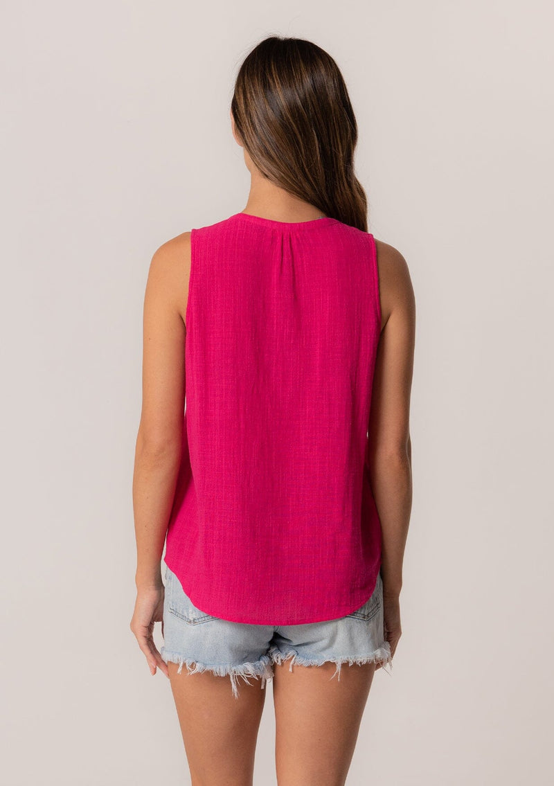 [Color: Fuchsia] A back facing image of a brunette model wearing a bohemian pink cotton tank top with a split v neckline, embroidered trim, and a relaxed fit.