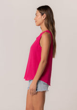 [Color: Fuchsia] A side facing image of a brunette model wearing a bohemian pink cotton tank top with a split v neckline, embroidered trim, and a relaxed fit.