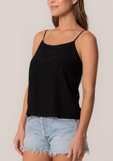 [Color: Black] A close up front facing image of a brunette model wearing a black bohemian spring camisole tank top with embroidered detail, adjustable spaghetti straps, a scooped neckline, and a self covered button up back detail.
