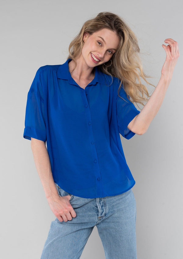 [Color: Cobalt] A front facing image of a blonde model wearing a bright blue sheer chiffon short sleeve button front blouse. With a self covered button front and a collared neckline.
