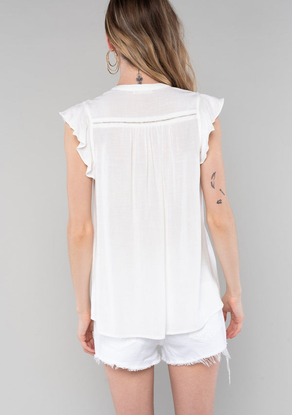 [Color: Vanilla] A back facing image of a blonde model wearing a solid white bohemian spring top. With short flutter cap sleeves, a self covered button front, neckline ties, and a relaxed fit. 