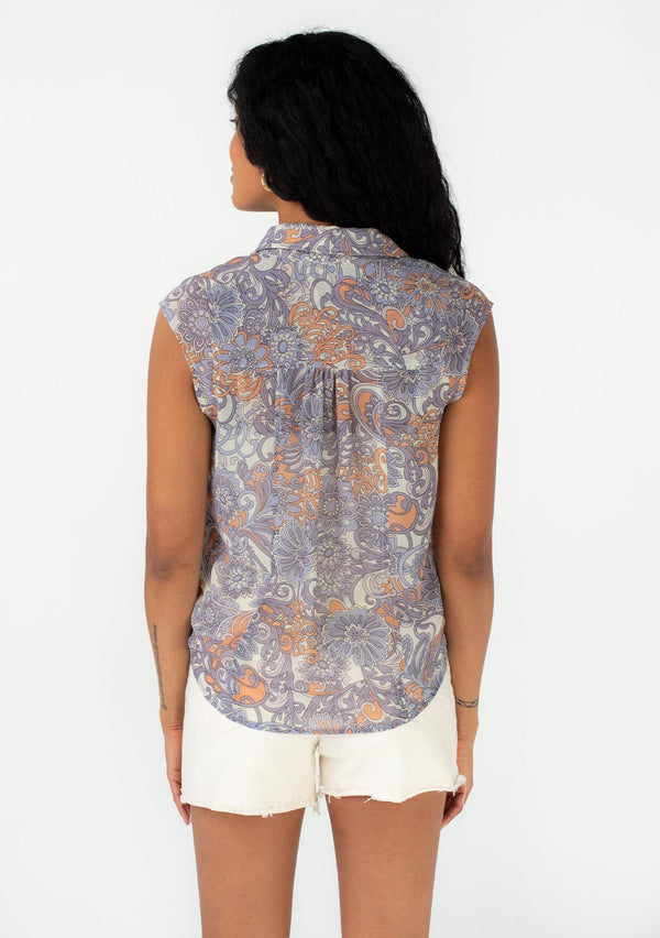 [Color: Ivory/Dusty Plum] A back facing image of a brunette model wearing a chiffon spring blouse in a purple retro floral print. With short cap sleeves, a button front, and a relaxed fit. 