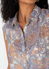 [Color: Ivory/Dusty Plum] A close up front facing image of a brunette model wearing a chiffon spring blouse in a purple retro floral print. With short cap sleeves, a button front, and a relaxed fit. 