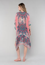 [Color: Coral/Teal] A back facing image of a blonde model wearing a bohemian resort mid length kimono in a coral and teal mixed floral print. With half length kimono sleeves, an open front, and side slits. 