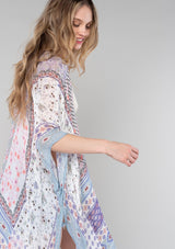 [Color: Ivory/Light Rose] A close up side facing image of a blonde model wearing a lightweight bohemian mid length kimono in an ivory and light pink mixed floral border print. With half length kimono sleeves, an open front, and side slits. 