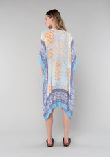 [Color: Ivory/Light Blue] A back facing image of a blonde model wearing a lightweight bohemian mid length kimono in an ivory and light blue mixed floral border print. With half length kimono sleeves, an open front, and side slits. 