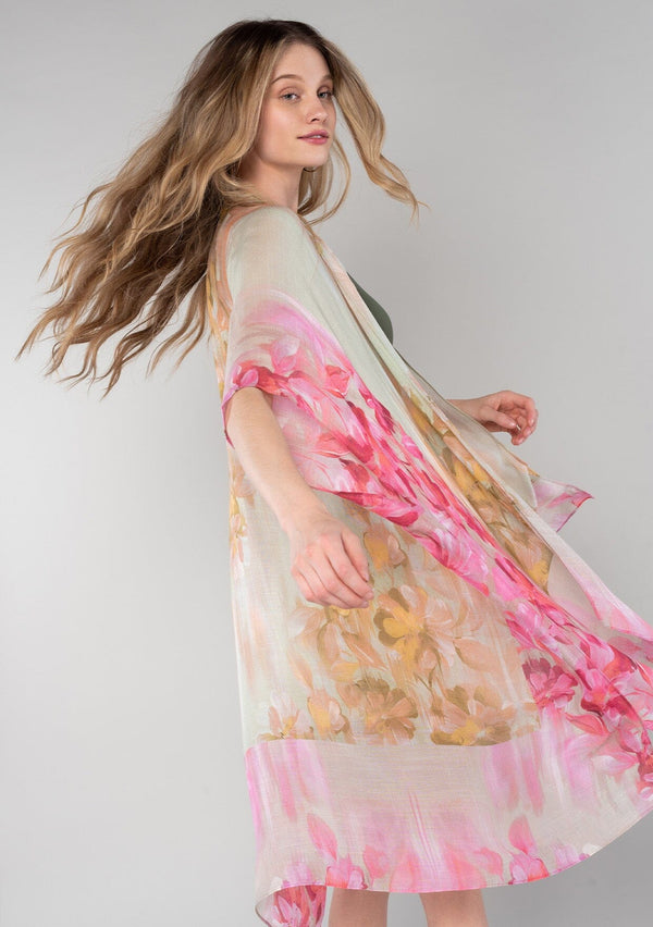 [Color: Mustard/Fuchsia] A half body side facing image of a blonde model wearing a lightweight bohemian mid length kimono in a mustard yellow and fuchsia pink watercolor floral print. With half length kimono sleeves, an open front, and side slits. 
