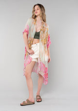 [Color: Mustard/Fuchsia] A full body front facing image of a blonde model wearing a lightweight bohemian mid length kimono in a mustard yellow and fuchsia pink watercolor floral print. With half length kimono sleeves, an open front, and side slits. 