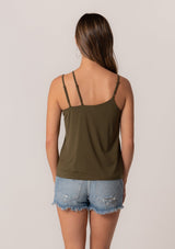 [Color: Military] A back facing image of a brunette model wearing a military green stretchy bamboo knit tank top with asymmetric spaghetti straps, a scoop neckline, and a relaxed slim fit.