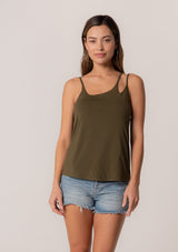 [Color: Military] A front facing image of a brunette model wearing a military green stretchy bamboo knit tank top with asymmetric spaghetti straps, a scoop neckline, and a relaxed slim fit.