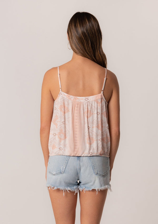 [Color: Natural/Peach] A back facing image of a brunette model wearing a summer tank top in a pink bohemian print. With adjustable spaghetti straps, a scoop neckline, a button front, a drawstring waist with tassel ties, and a relaxed fit. 