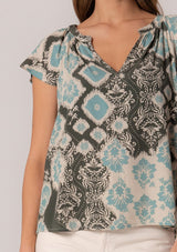 [Color: Black/Aqua] A close up front facing image of a brunette model wearing a classic short sleeve summer top in a green bohemian print. With short flutter sleeves and a v neckline. 