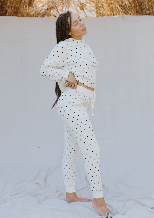 [Color: Ivory/Black] A woman standing outside wearing a polka dot jogging pant. Featuring a drawstring waist, a tapered leg, and side pockets.
