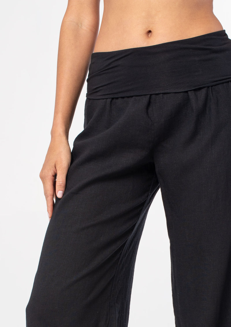 [Color: Black] A model wearing a cool black lounge pant in a cotton linen blend. With a long wide leg and a contrast knit fold over waistband.