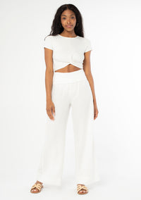 [Color: Cloud] A model wearing a cool white lounge pant in a cotton linen blend. With a long wide leg and a contrast knit fold over waistband.