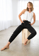[Color: Black] A model wearing a woven jogger pant. With essential cargo style side pockets, an elastic drawstring waist, and ankle length tapered leg.