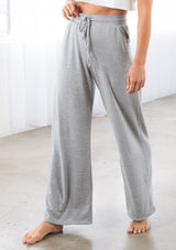 [Color: Light Heather Grey] A model wearing a soft knit wide palazzo leg pant. Featuring an elastic drawstring waistband and side pockets.